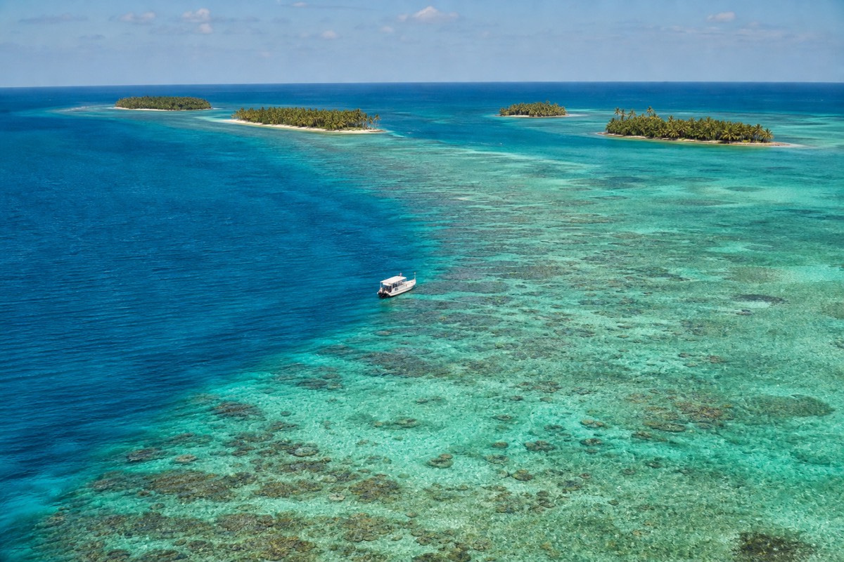Snorkelers floating above coral heads on the Belize Barrier Reef in clear turquoise water